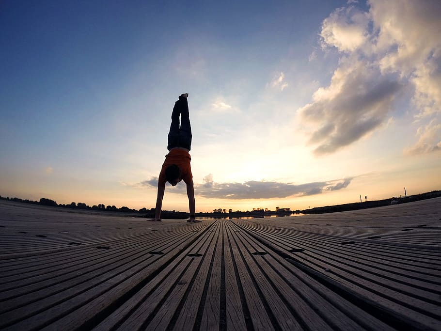 person on orange shirt doing hand stand on brown pavement, handstand HD wallpaper