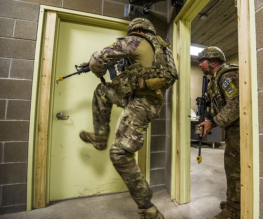 two army officers holding assault rifles beside door, soldiers