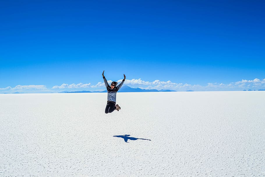 woman jumping under blue skyt, person taking jump shot on seashore HD wallpaper