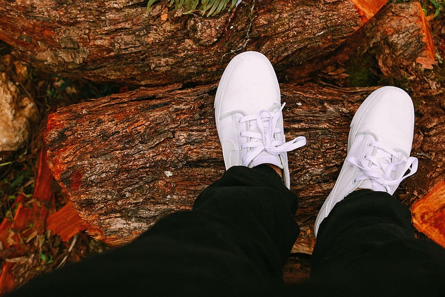 person standing on brown tree log, shoes, feet, white, clean