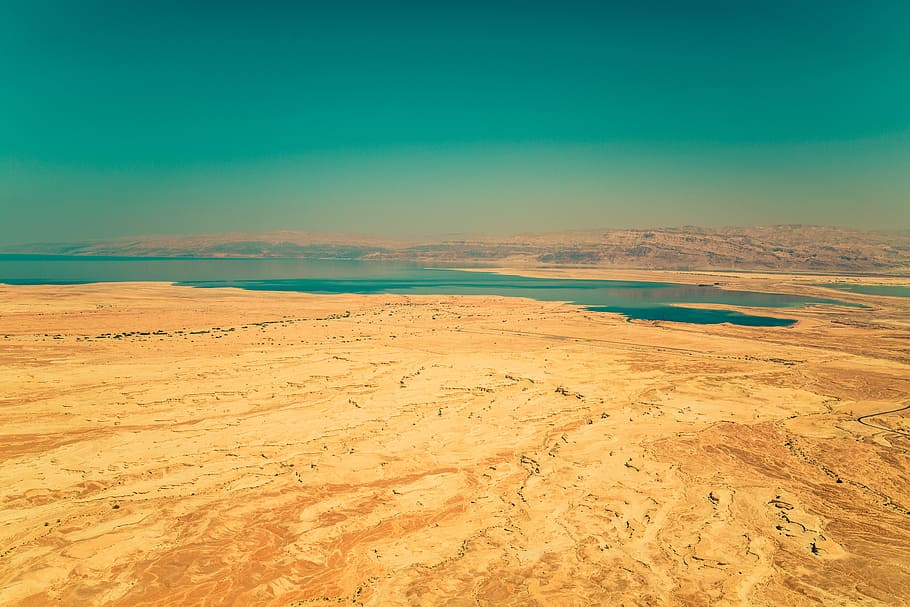 calm green sea beside brown sand under green sky, photograph of body of water between brown rock and soil HD wallpaper