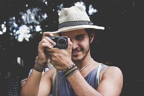 selective focus photo of man holding black compact camera, man in brown fedora hat taking photo HD wallpaper