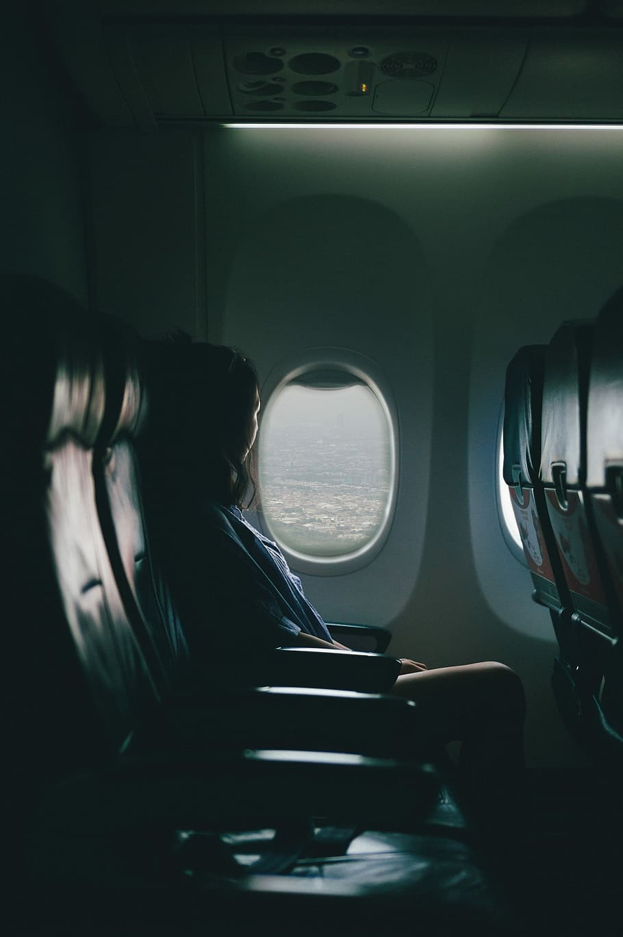 woman sits on seat near window inside plane, woman seating on black leather chair beside window