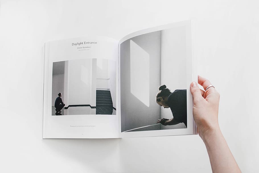 person reading book on white surface, person holding book, magazine HD wallpaper