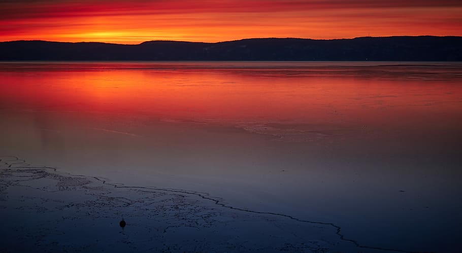 calm body of water, silhouette of mountain across body of water during orange sunset HD wallpaper