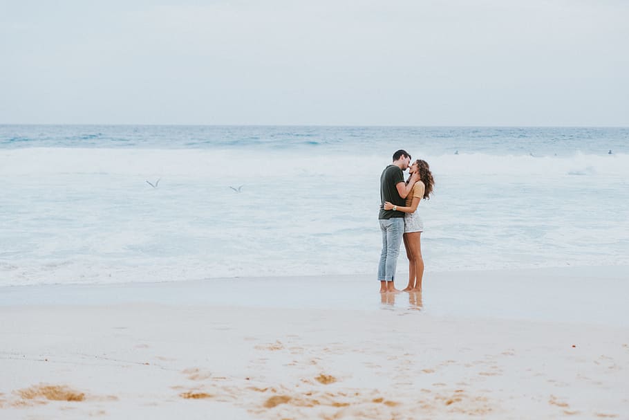 man and woman kissing each other on the seashore, man and woman kissing near beach