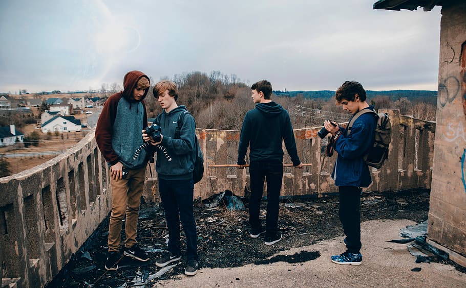 4 men in blue and grey jackets standing outside the house during daytime HD wallpaper