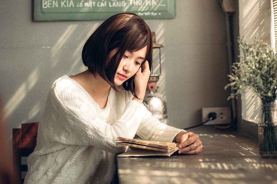 woman wearing long-sleeved shirt while reading book, camera raw