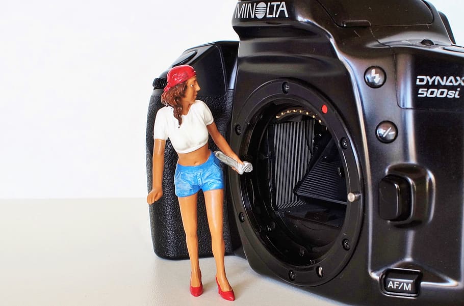 girl doll in front of black Minolta camera, konica, old camera
