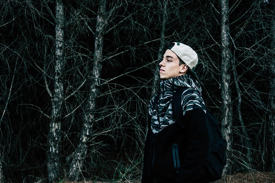 man in black and gray jacket standing near gray tree, man wearing white hat near trees HD wallpaper
