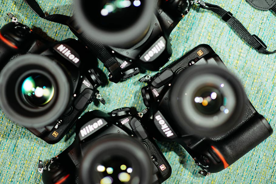 four black Nikon DSLR cameras on green textile, four black Nikon DSLR cameras on teal fabric sheet HD wallpaper
