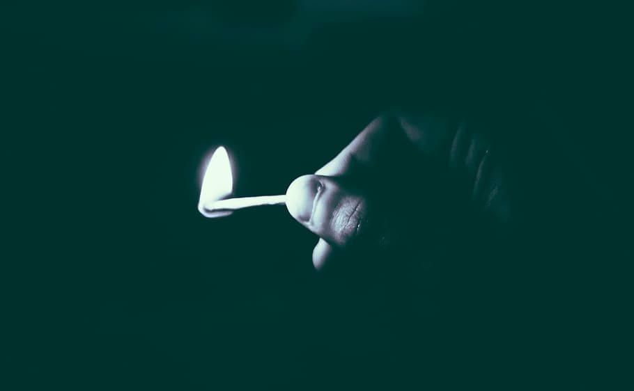 grayscale photo of person holding lit matchstick, fire, dark
