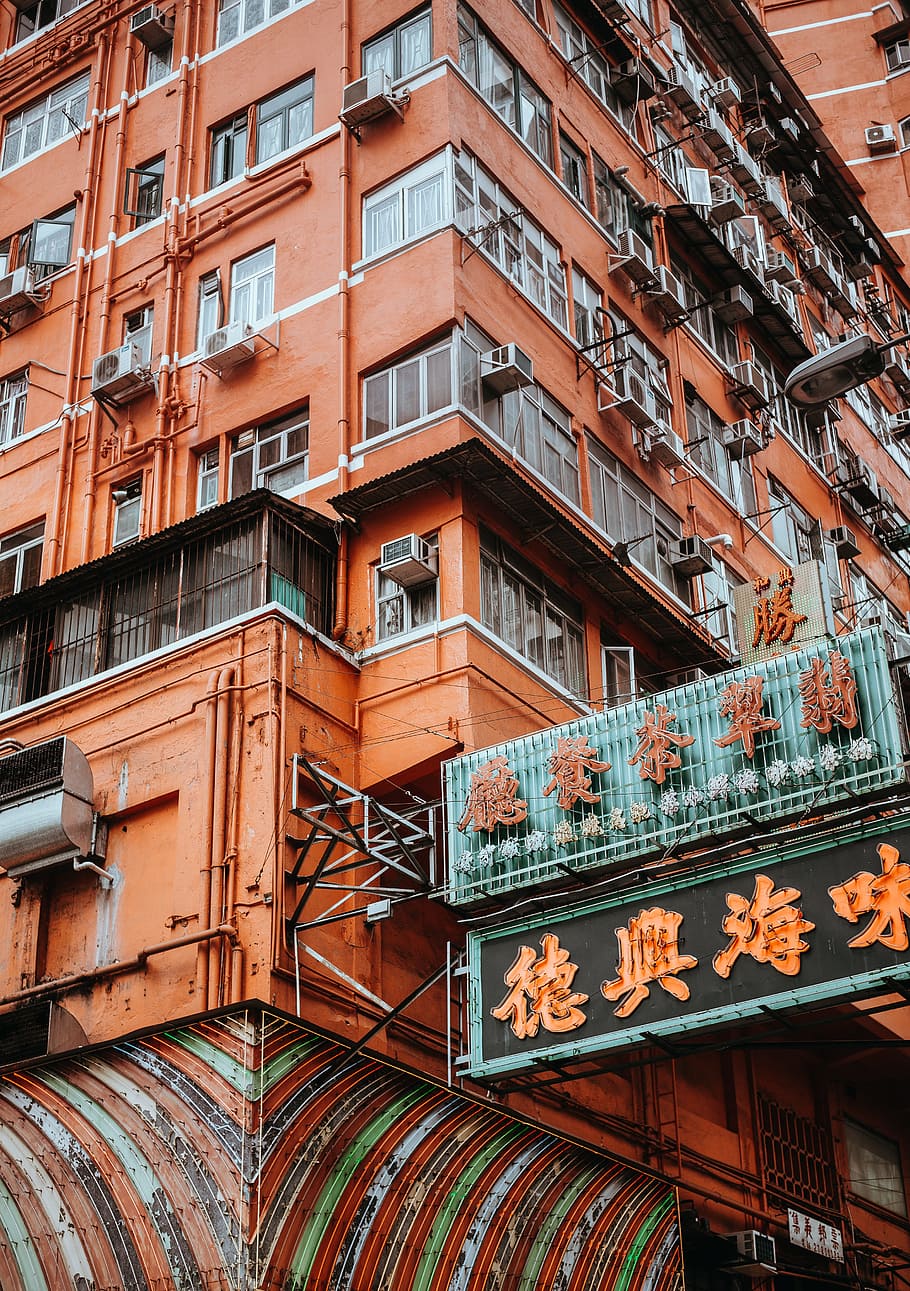 orange text with black background signage beside building structure, brown building with AC units HD wallpaper