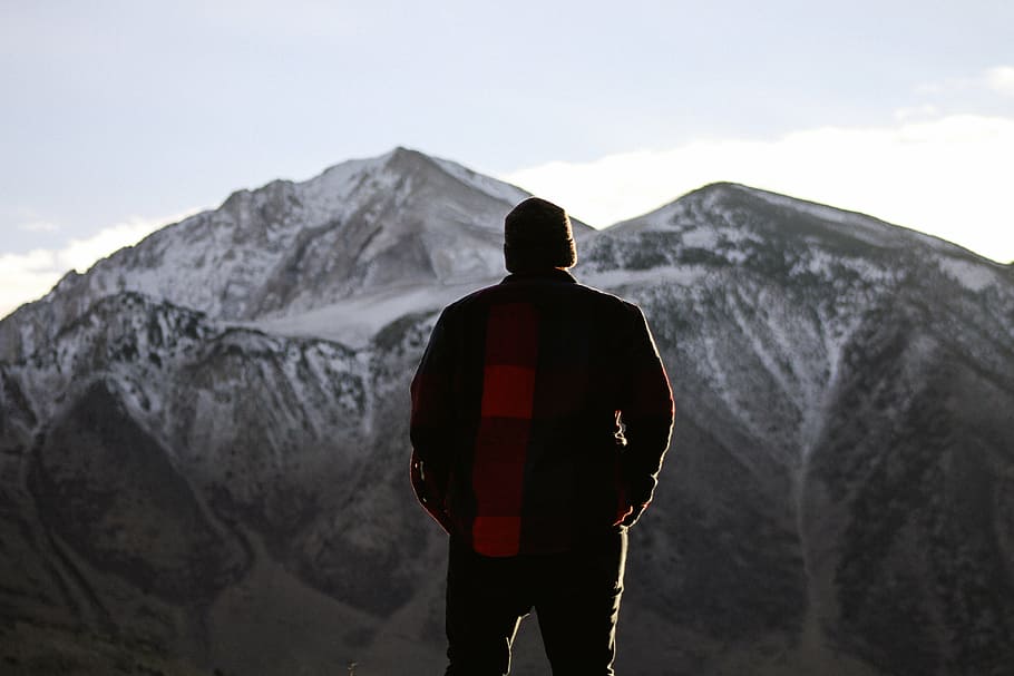 man standing on ground and facing at mountains, people, alone