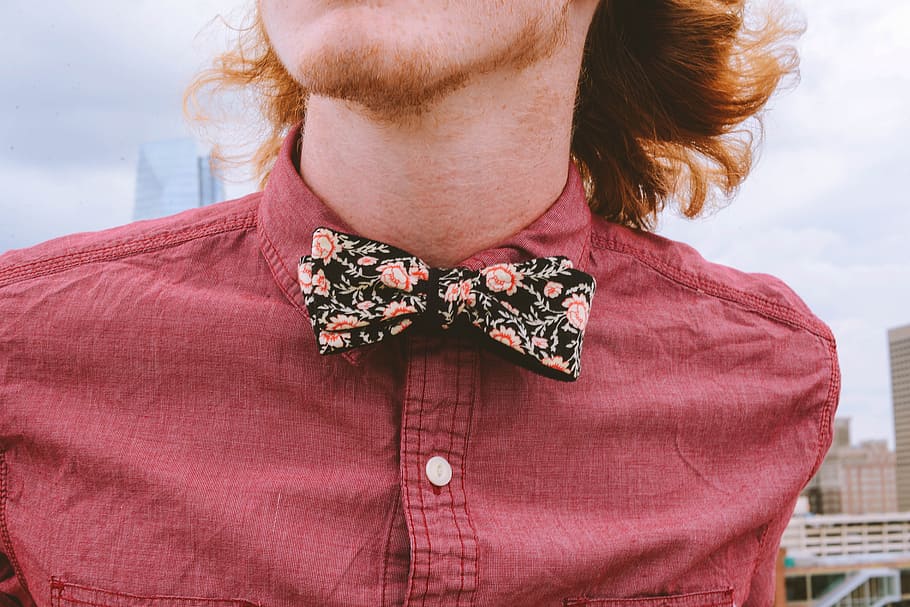 closeup photography of person wearing floral bowtie and red dress shirt, person wearing pink collared top with bow
