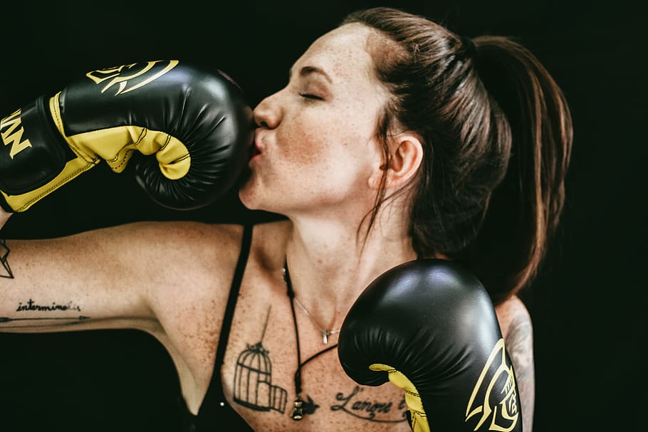woman kissing black leather boxing gloves, tattooed, black and yellow