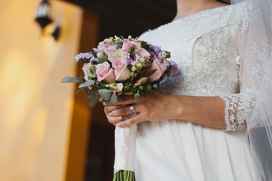 bride holding pink bouquet of rose, newlywed woman holding boquet