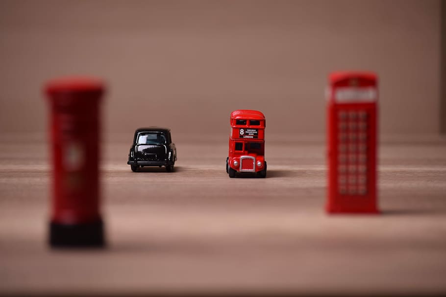 two red and black toy cars near telephone booth, city, street