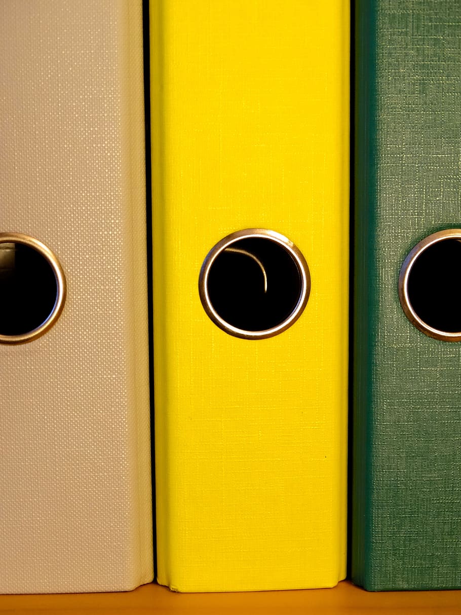 close-up of three green, yellow, and brown binders on brown surface HD wallpaper