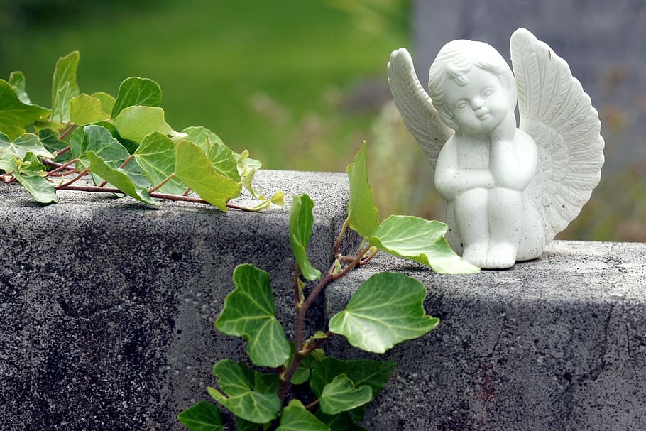 white ceramic cherub on gray concrete surface, angel, grabschmuck