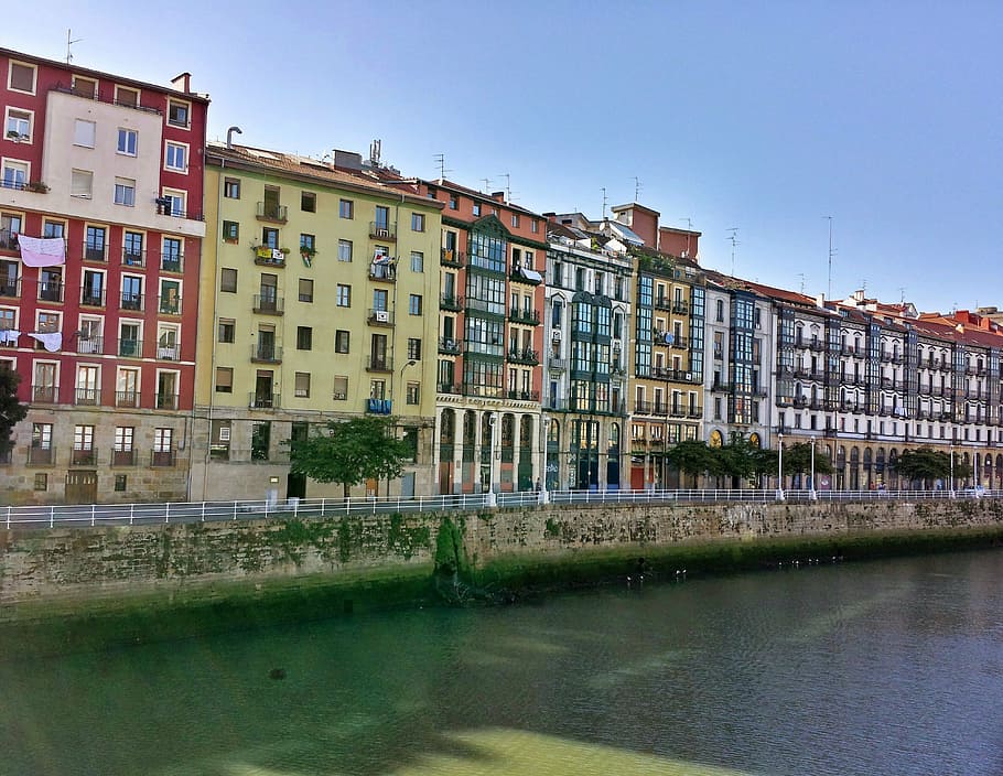 multicolored concrete building lot near river, bilbao, ria HD wallpaper