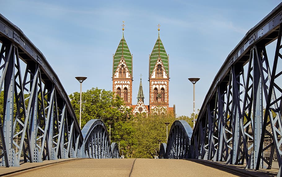 gray steel bridge with white and green castle in front, church