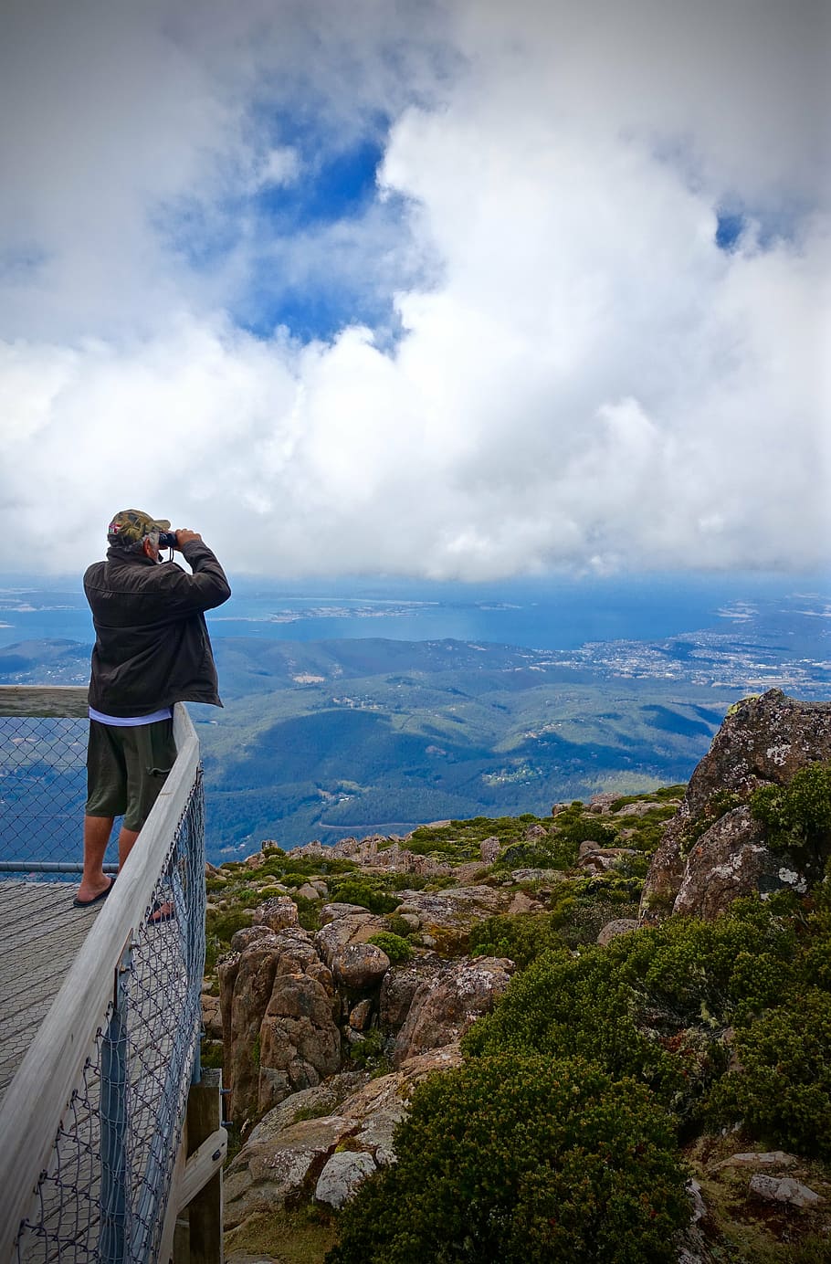 man standing on balcony viewing green landscape during daytime HD wallpaper