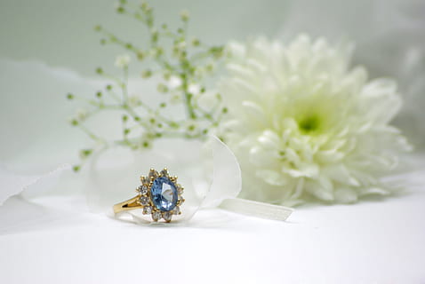 gold-colored blue stone encrusted ring beside white flower HD wallpaper