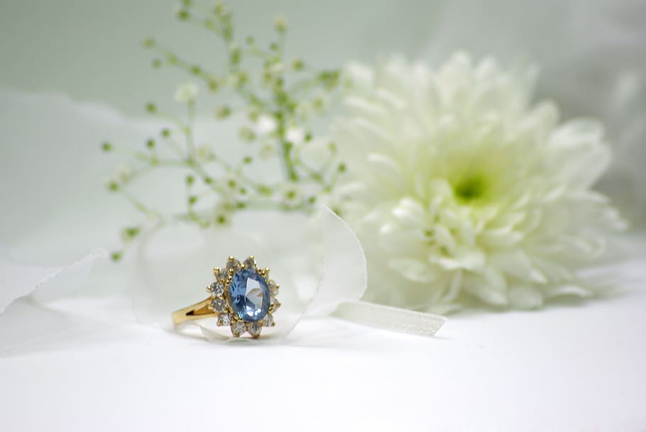 gold-colored blue stone encrusted ring beside white flower HD wallpaper