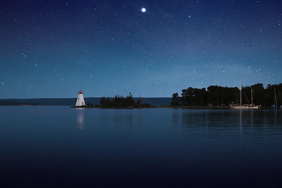 photograph of white lighthouse near calm body of water at night, lighthouse beside body of water under starry sky HD wallpaper