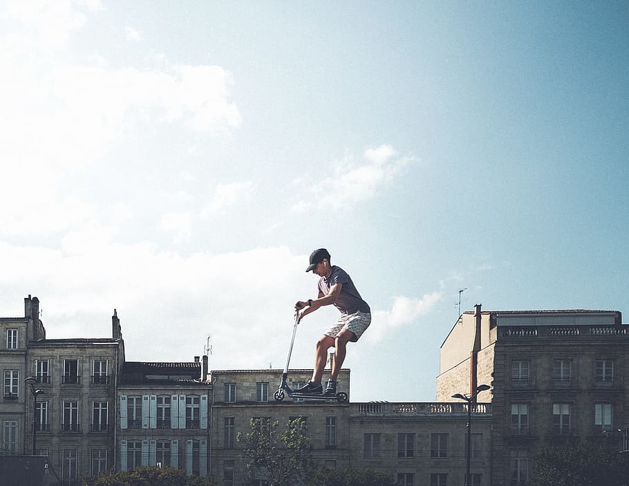 man riding on black kick scooter, person riding kick scooter on top of building illustration HD wallpaper