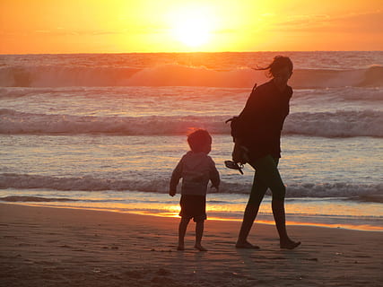 woman and boy on sand near body of water during golden hour HD wallpaper