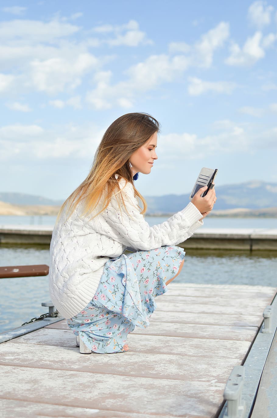 woman using smartphone while sitting of dock during daytime, woman sitting on dock while holding smartphone HD wallpaper