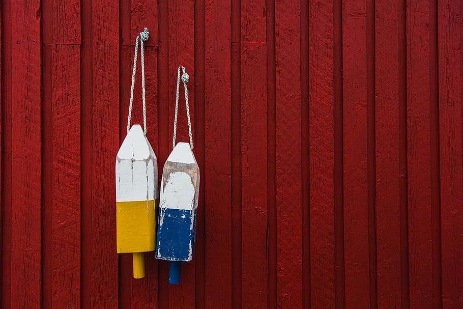 two yellow and blue hanging decors behind red wall, two yellow and blue wooden decor hanging by red wall HD wallpaper