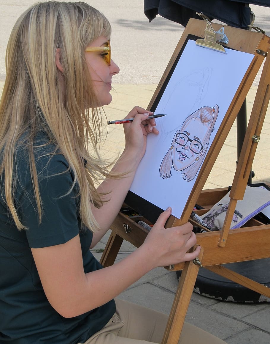girl sketching white sitting in front of easel, caricature artist