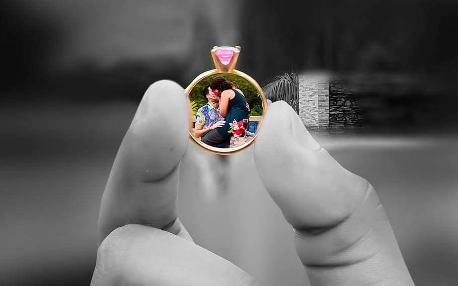 person holding gold-colored ring with pink gemstone encrust, wedding