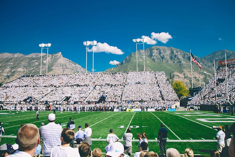 people watching football game under white clouds and blue sky at daytime