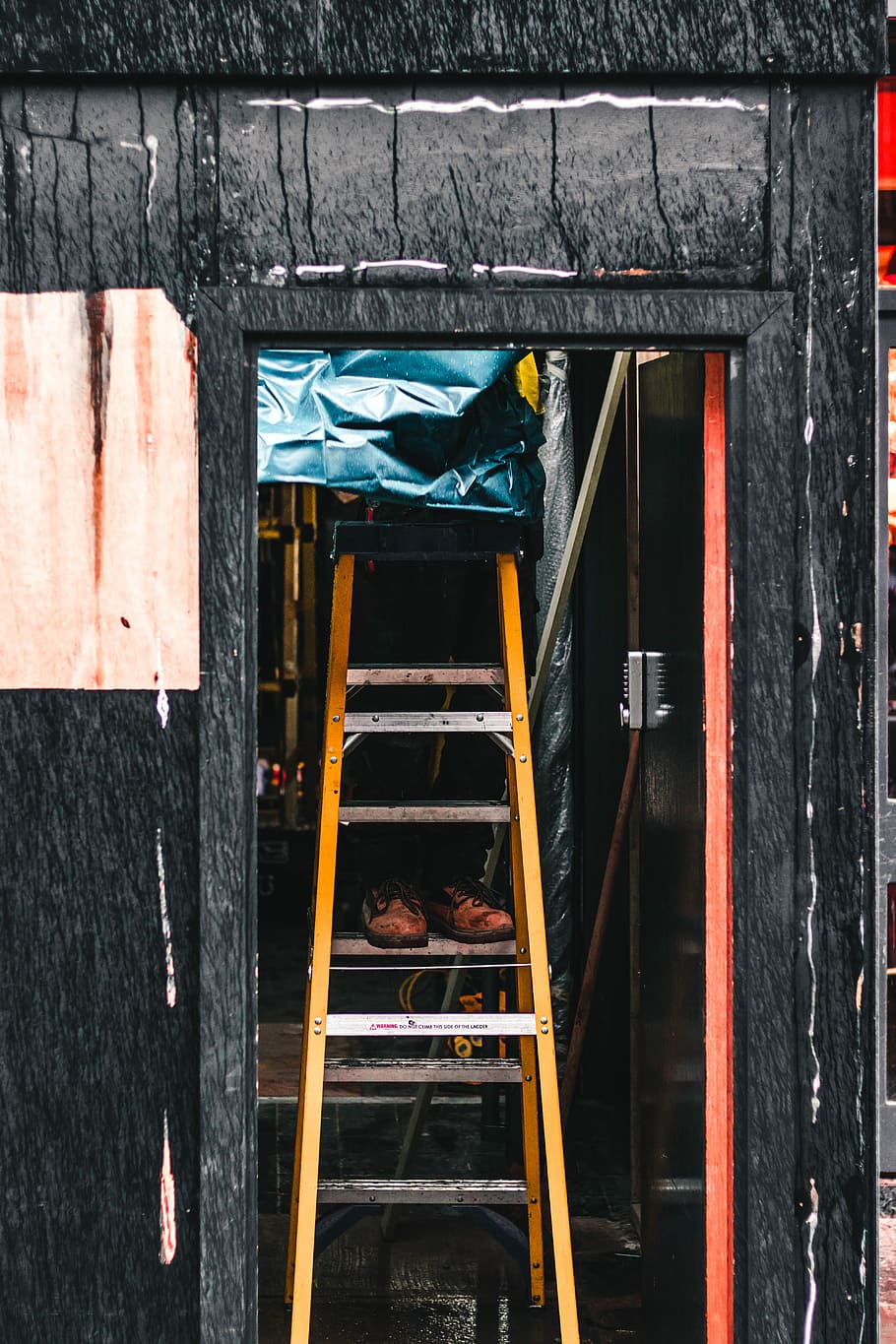 photography of person on A-frame ladder near door, orange A-frame ladder inside black wall HD wallpaper