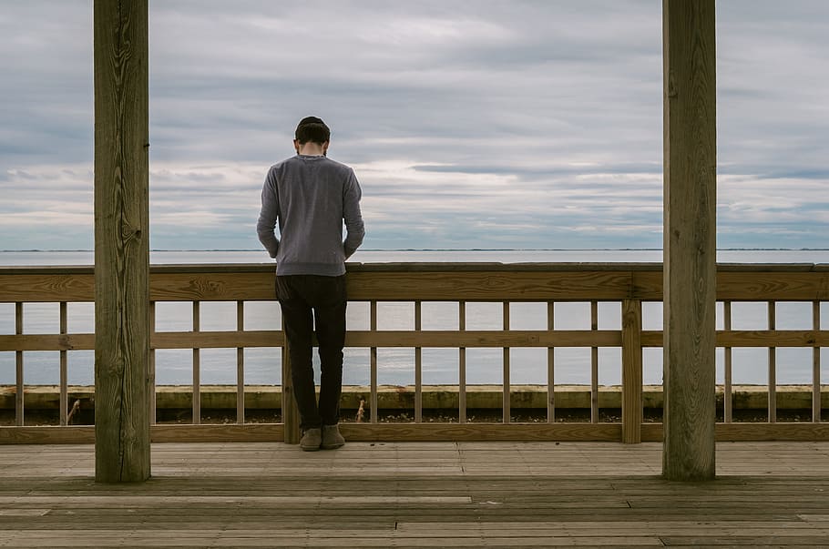 man leaning on wooden fence fronting ocean, people, guy, standing HD wallpaper