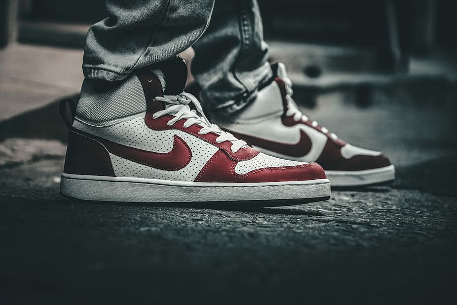 person wearing pair of white-and-red Nike high-top sneakers, selective focus photography of pairs of white-and-red Nike sneakers