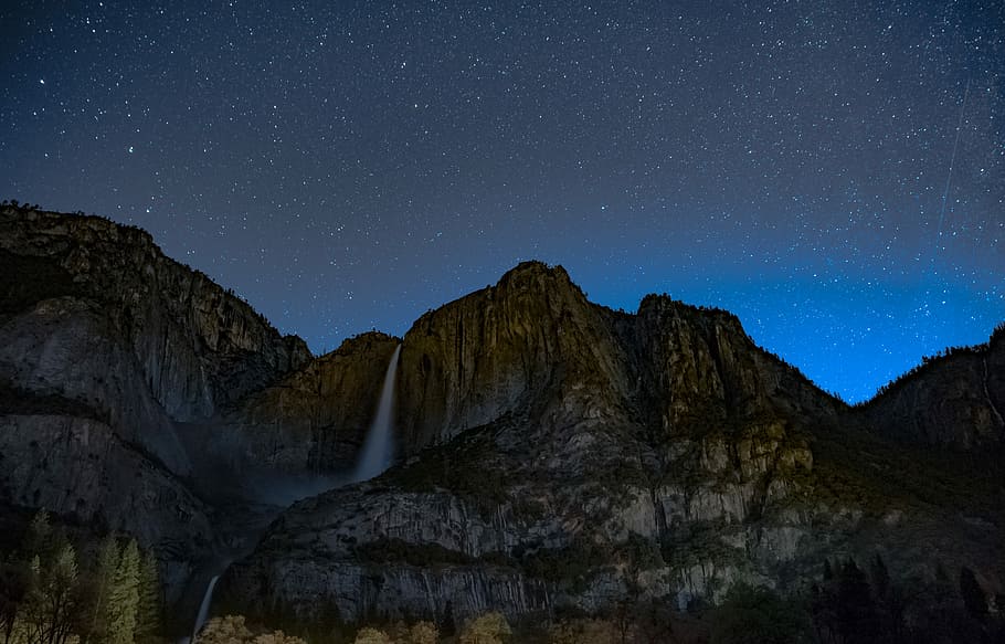 waterfalls on brown rugged mountain under blue sky at nighttime, waterfalls near rocky mountain during day time HD wallpaper