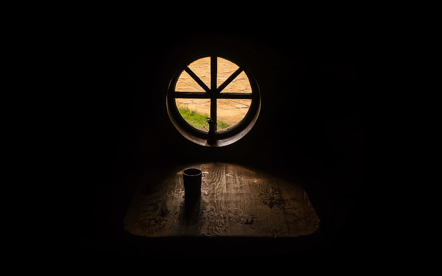 drinking cup on brown wooden table near round attic window, attic window