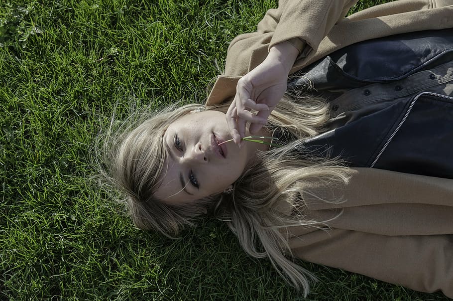 women's wearing brown coat lying on green grass field, girl, meadow