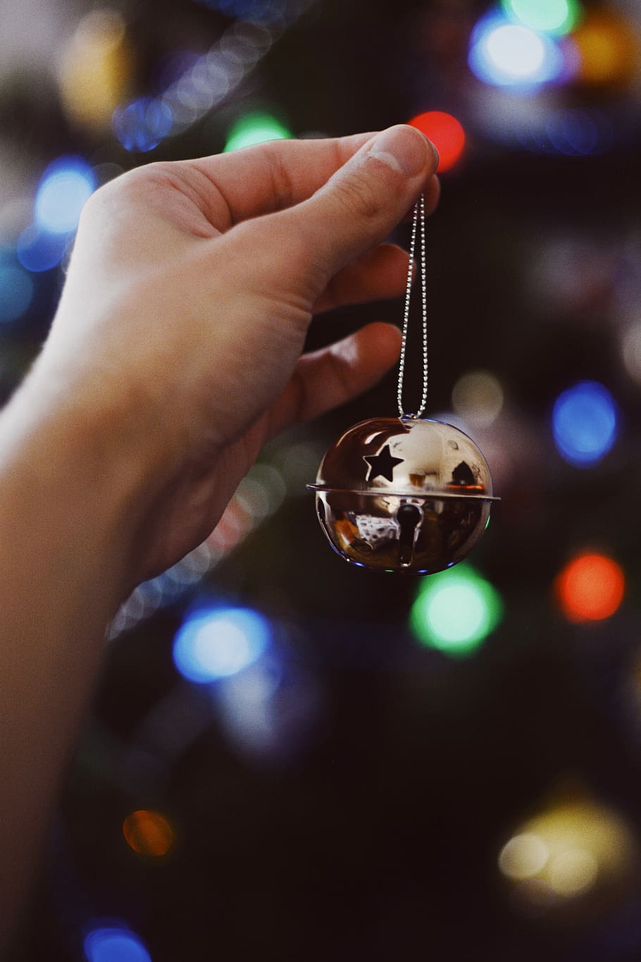 person holding Christmas ornament, person holding gold-colored bell HD wallpaper