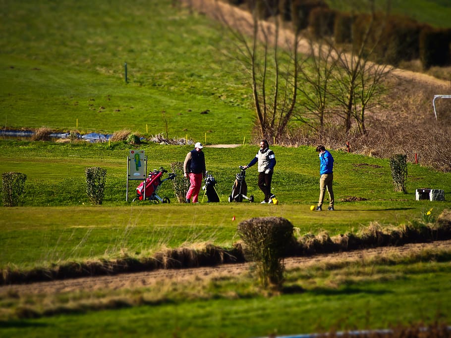 three men playing golf on field across hill during daytime HD wallpaper