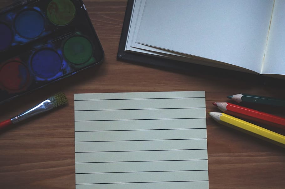 white paper between water color palette and color pencils on brown wooden surface HD wallpaper
