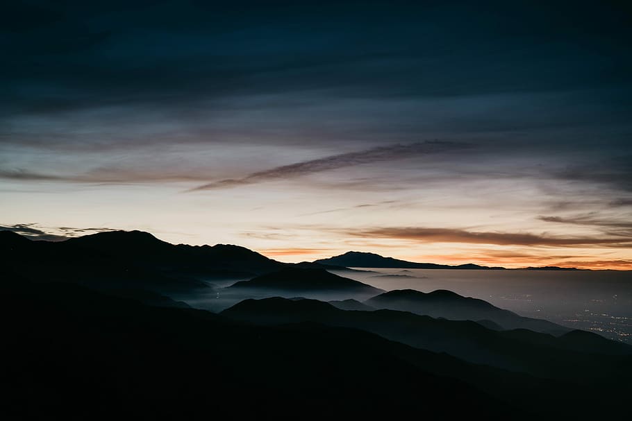 aerial photography of mountain range near body of water, silhouette of mountains under cloudy sky HD wallpaper