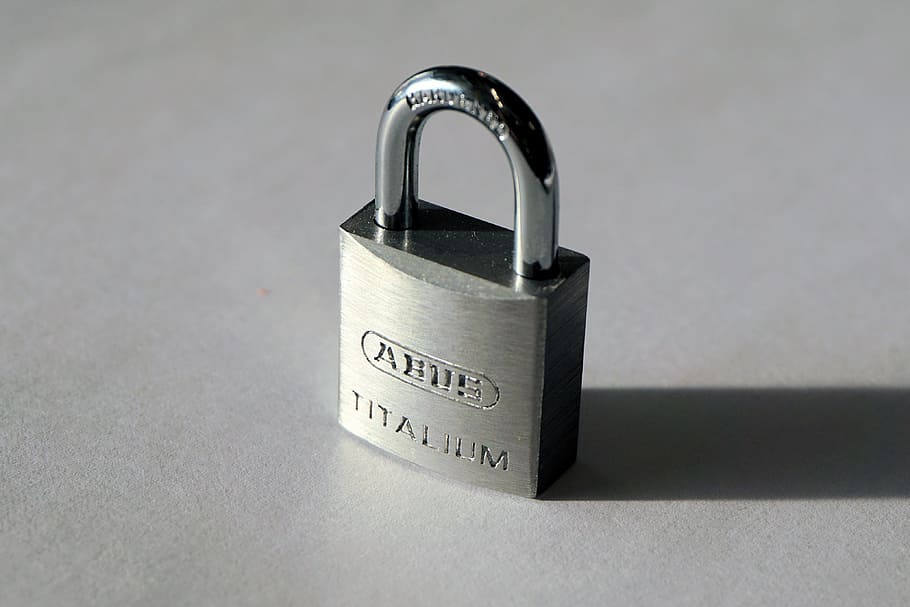 gray Titalium padlock with shadow on gray surface in close-up photography