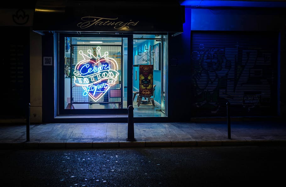 landscape photography of neon tattoo sign during nighttime, neon lighted storefront near road