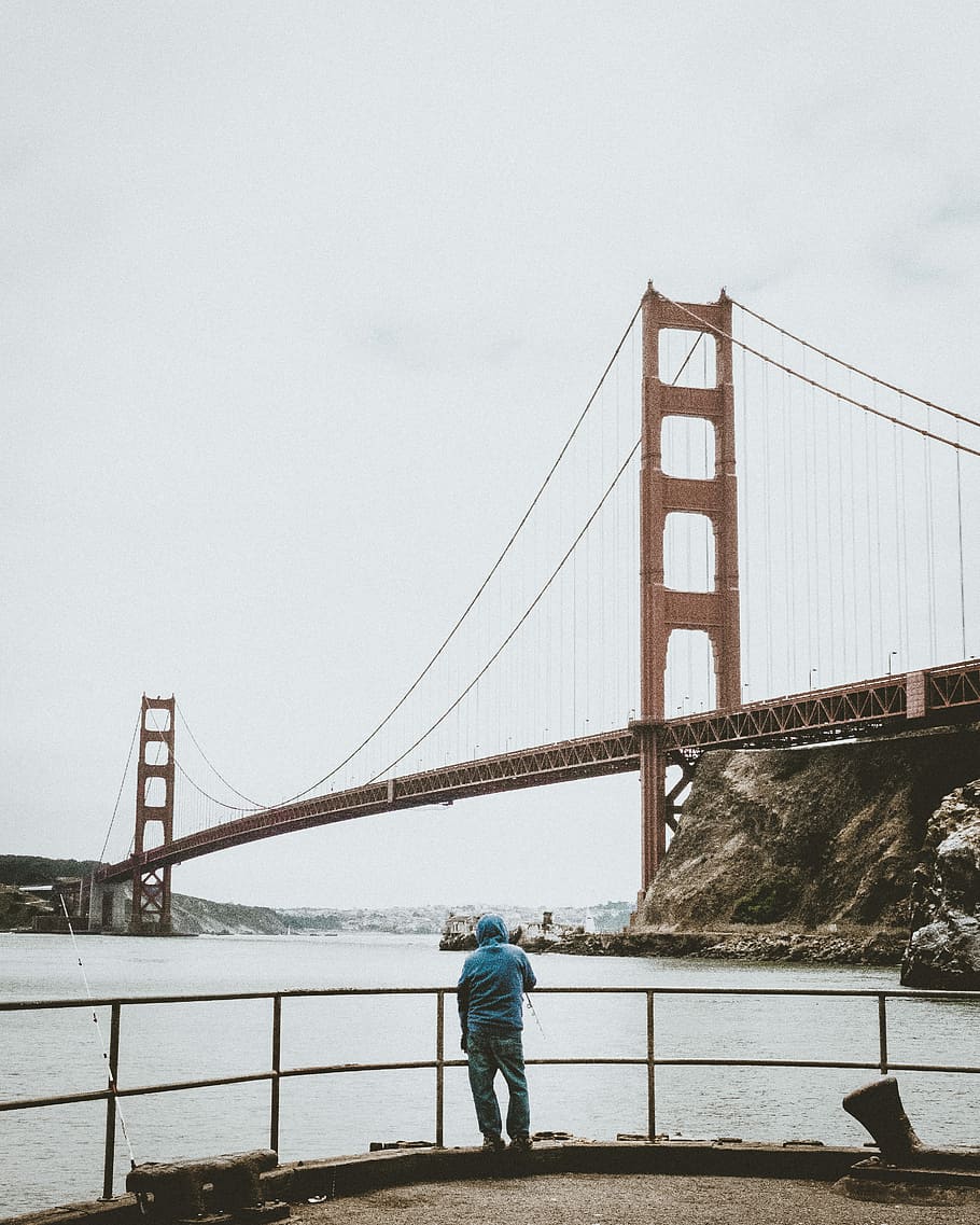 man standing in front of black fence, man standing near Golden Gate Bridge during daytime HD wallpaper